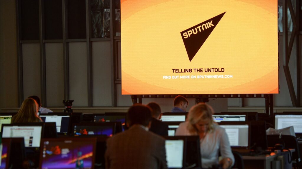 Sputnik Azerbaijan newsroom with journalists and “Telling the Untold” slogan on screen.