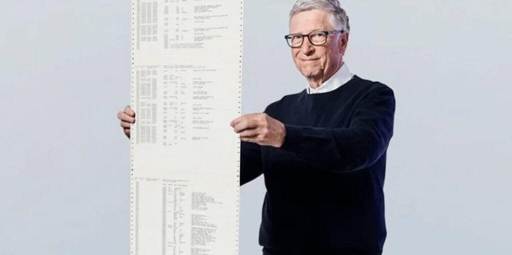 Bill Gates memegang cetakan kode panjang yang terkait dengan sejarah MS DOS.