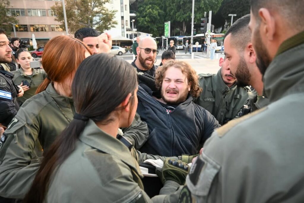 Israeli police officers detaining anti-war activist Itamar Greenberg during a protest in Tel Aviv.