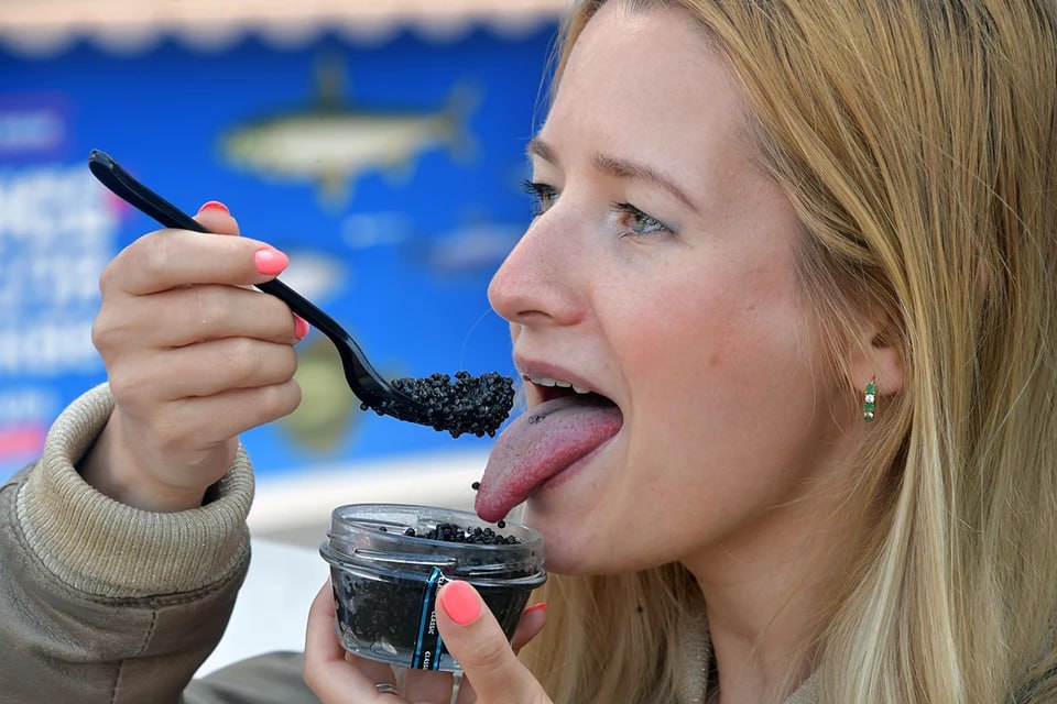 Perempuan sedang mencicipi kaviar hitam dalam festival kuliner Rusia.